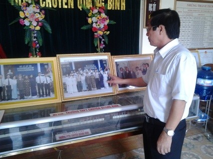 Thầy Hoàng Thanh Cảnh - Hiệu trưởng Trường THPT chuyên Quảng Bình đang giới thiệu những bức ảnh Đại tướng Võ Nguyên Giáp chụp cùng giáo viên, học sinh trong trường trong những lần khác nhau